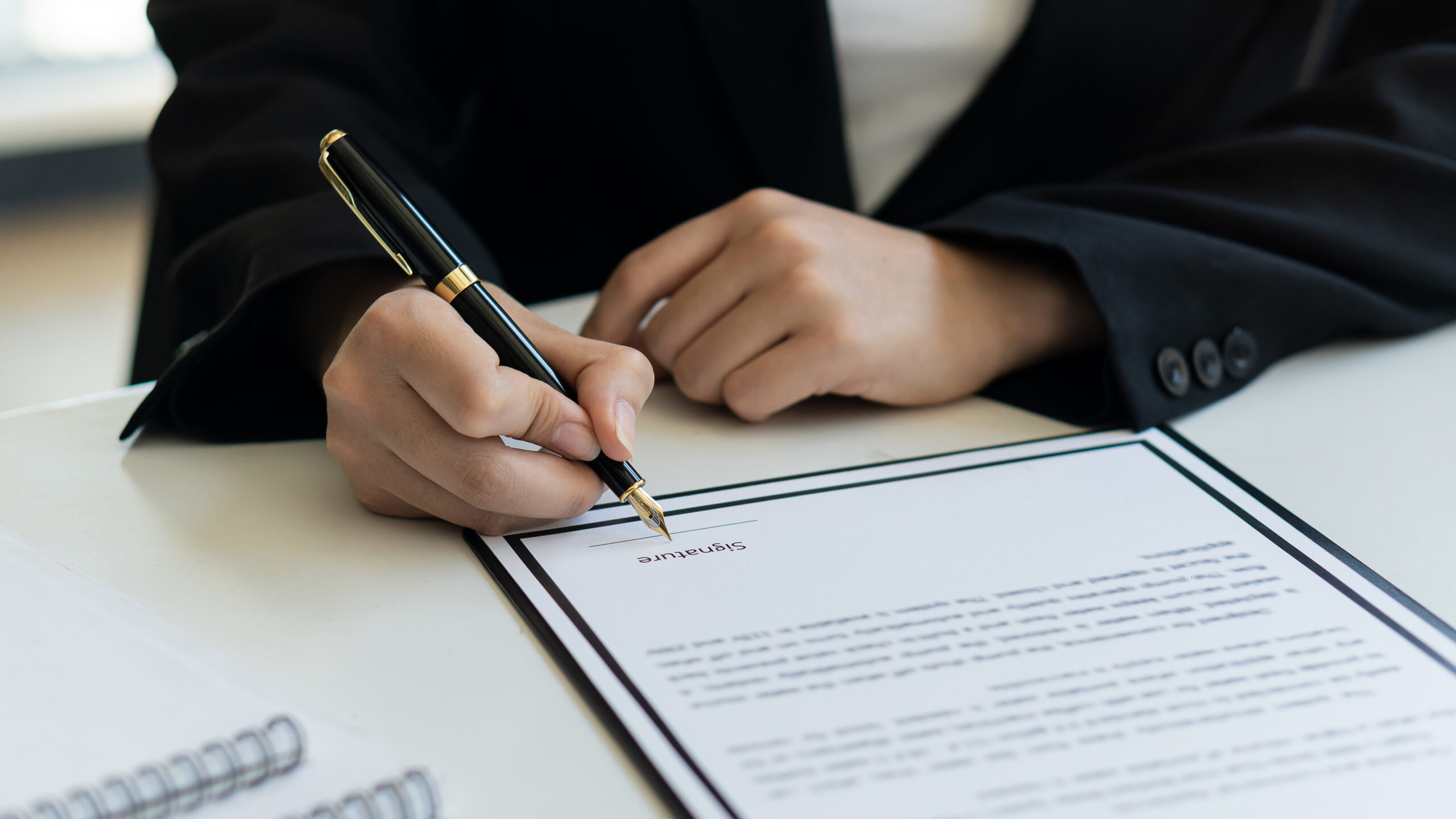 A young woman signing a estate planning document.